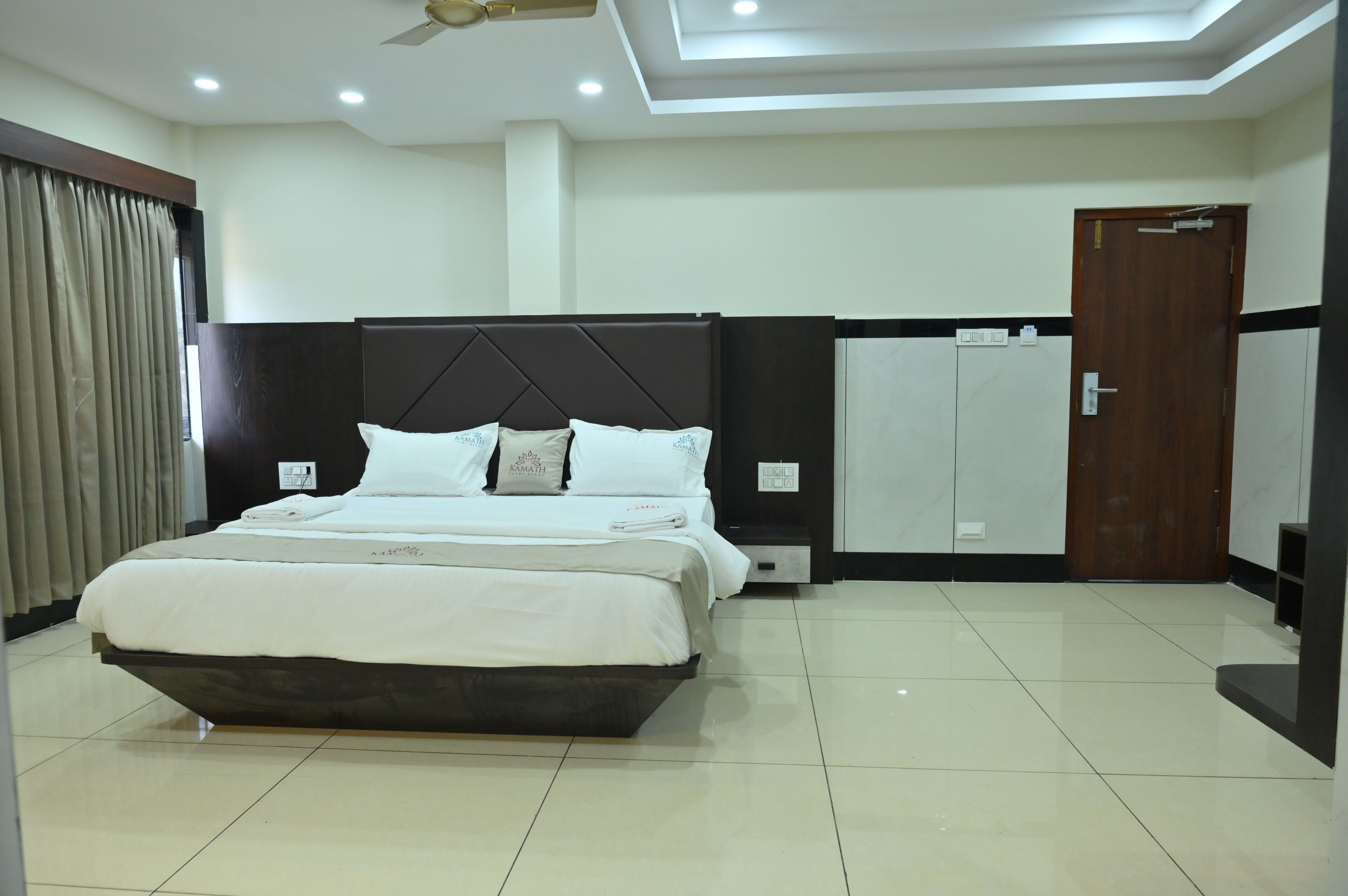 A hotel room with a bed, wardrobe, and a ceiling fan.