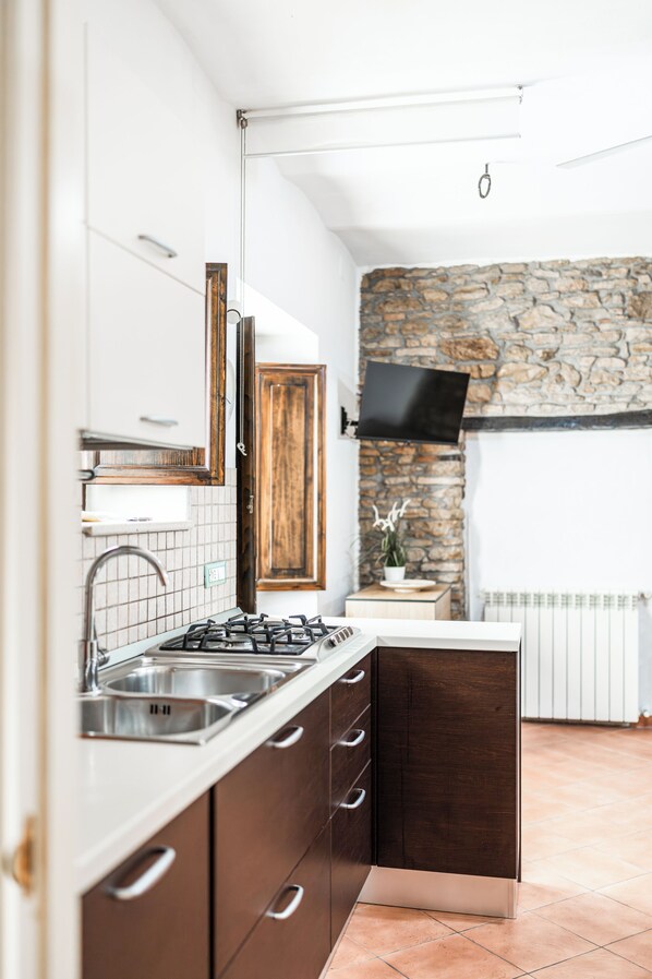 A modern kitchen with a stone wall, a built-in stove, and a large window. - La Casa di Zia Rita (San Giacomo degli Schiavoni)