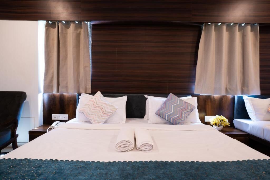A hotel room with a large bed, two nightstands, a chair, and a wooden headboard.