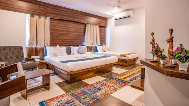 Un dormitorio moderno con una cama grande, un escritorio, una silla, un sofá y una estantería decorativa con plantas.