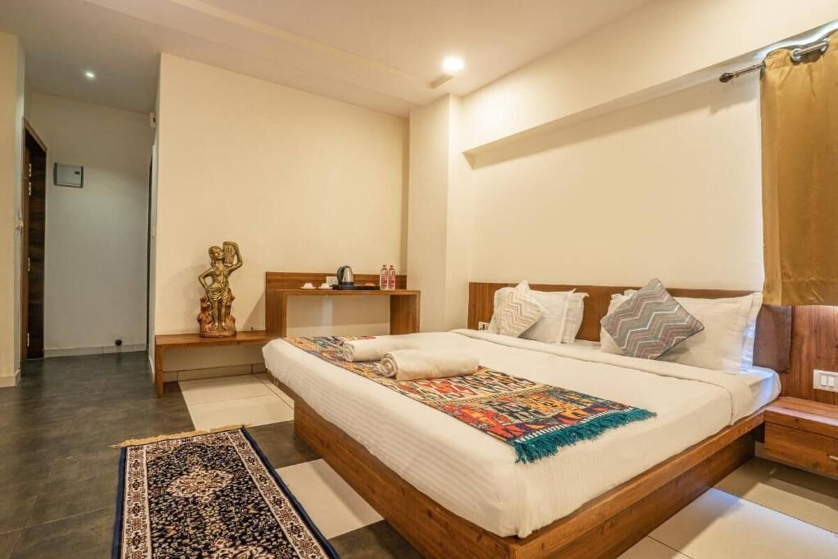 A bedroom with a wooden bed, white bedding, a patterned rug, and a nightstand.