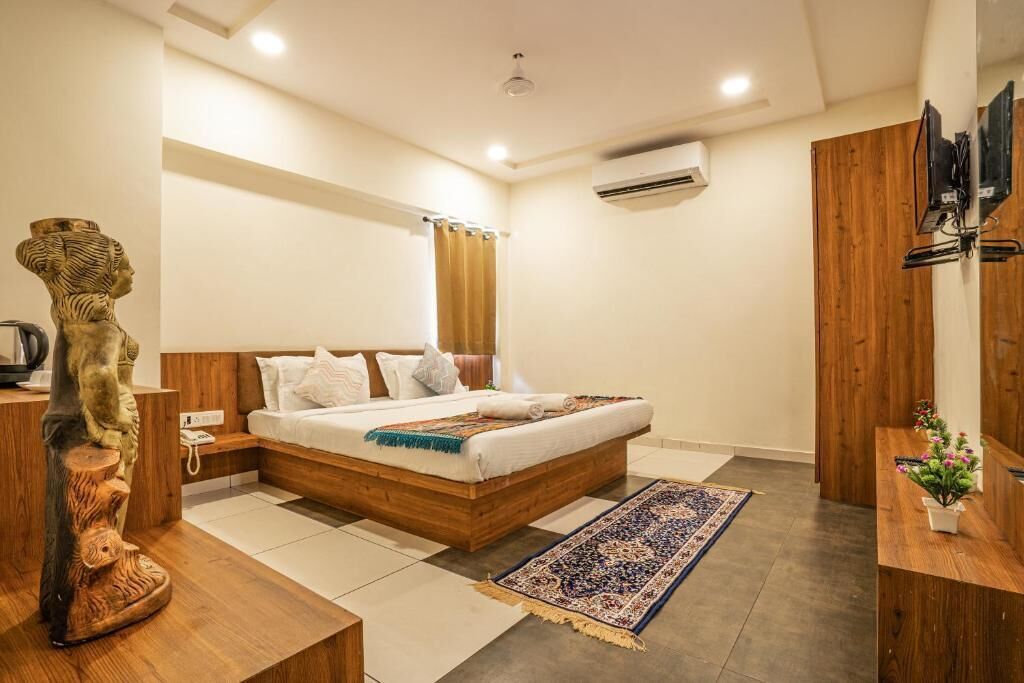 Un dormitorio moderno con una cama de madera, una mesita de noche, una escultura decorativa de madera, una alfombra grande y un televisor montado en la pared.