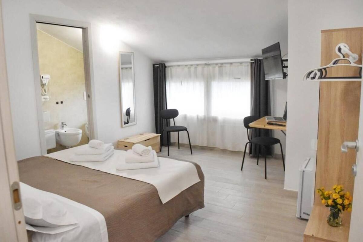 A hotel room with a bed, a desk, a chair, a TV, and a wardrobe.