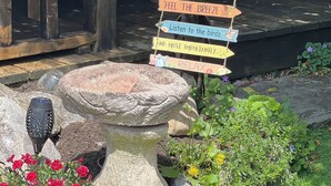 A rustic outdoor setting with a wooden structure, a stone birdbath, and a signpost with wooden signs. - Quiet retreat near the interchange with woodland views. (Patchway)
