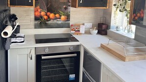 A modern kitchen with black and white cabinets, a built-in oven, and a backsplash with a fruit display. - Quiet retreat near the interchange with woodland views. (Patchway)