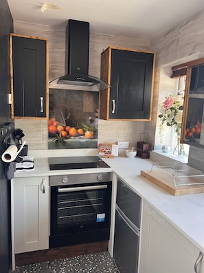 A modern kitchen with black and white cabinets, a built-in oven, and a backsplash with a fruit display.
