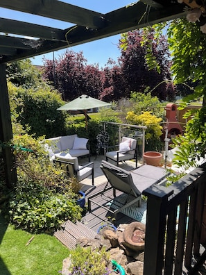 A covered patio area with outdoor furniture, a pergola, and a variety of plants.
