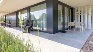 A modern building with large windows, a covered patio area, and outdoor seating. - Air Conditioned Apartment | Pool | Terrace | Close to Lake and Beach (Mielno)