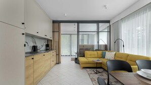 A modern kitchen with wooden cabinets, a dining area with a yellow sofa, and a large window providing natural light. - Air Conditioned Apartment | Pool | Terrace | Close to Lake and Beach (Mielno)