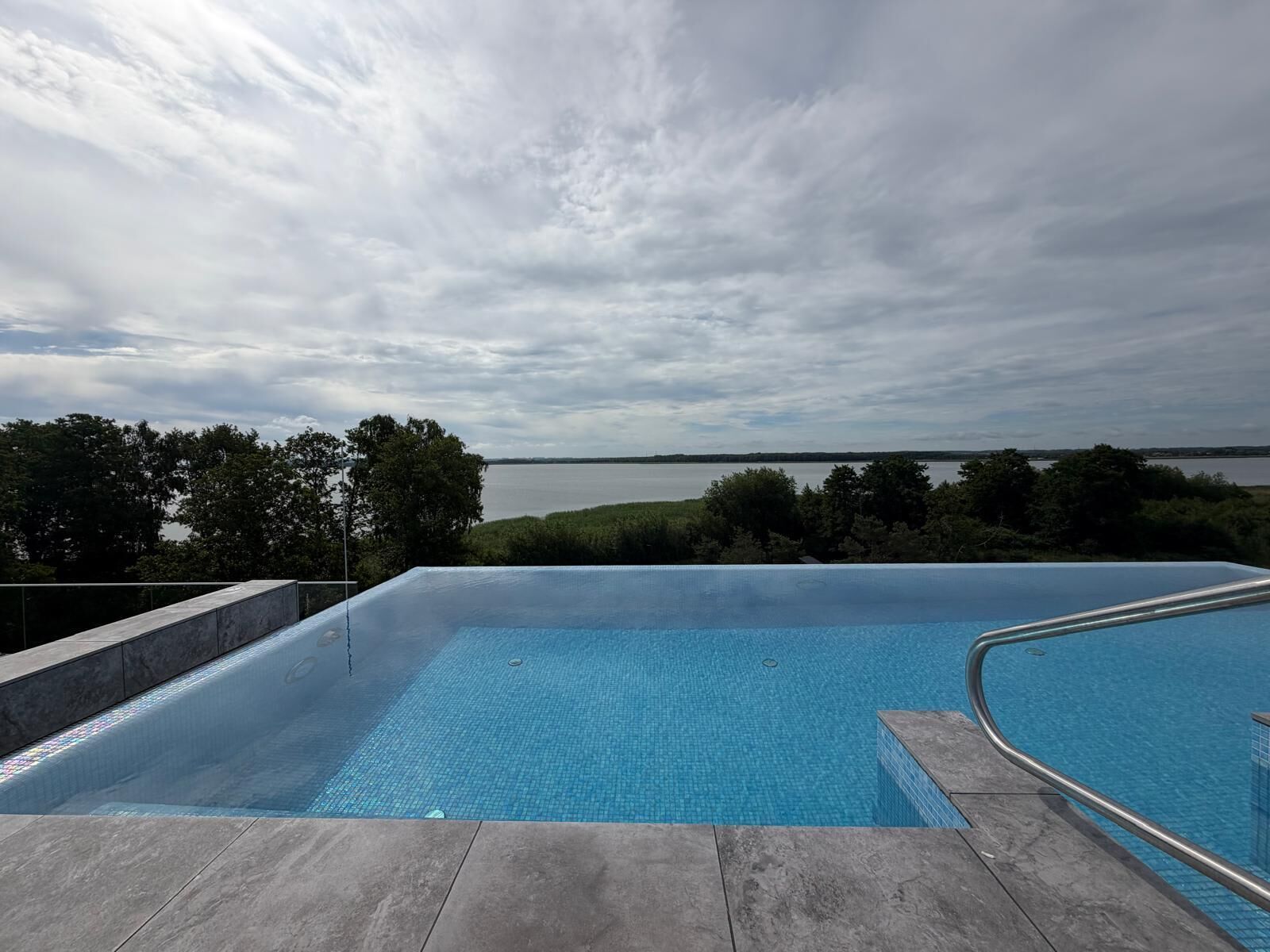 A swimming pool with a view of a lake and trees.