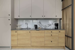 Een moderne keuken met een marmeren achterwand, houten kastjes en een koffiezetapparaat.