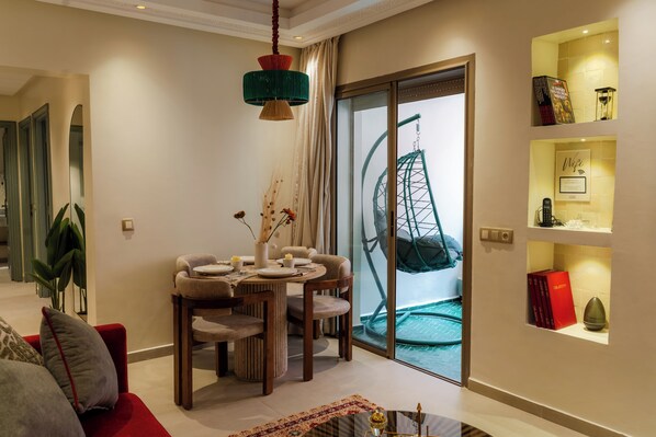 A modern living room with a dining area, a large window with a view of a Ferris wheel, and a bookshelf with books and decorative items. - Gigi Apartment with Pool & Parking (Marrakesh)