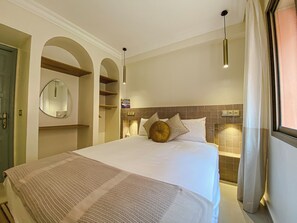 A hotel room with a bed, a mirror, a shelf, and a window with curtains. - Gigi Apartment with Pool & Parking (Marrakesh)