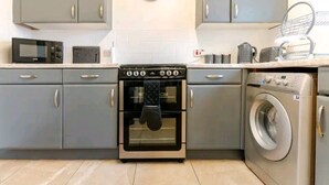 Eine Küche mit grauen Schränken, einer Mikrowelle, einem Backofen und einer Waschmaschine.