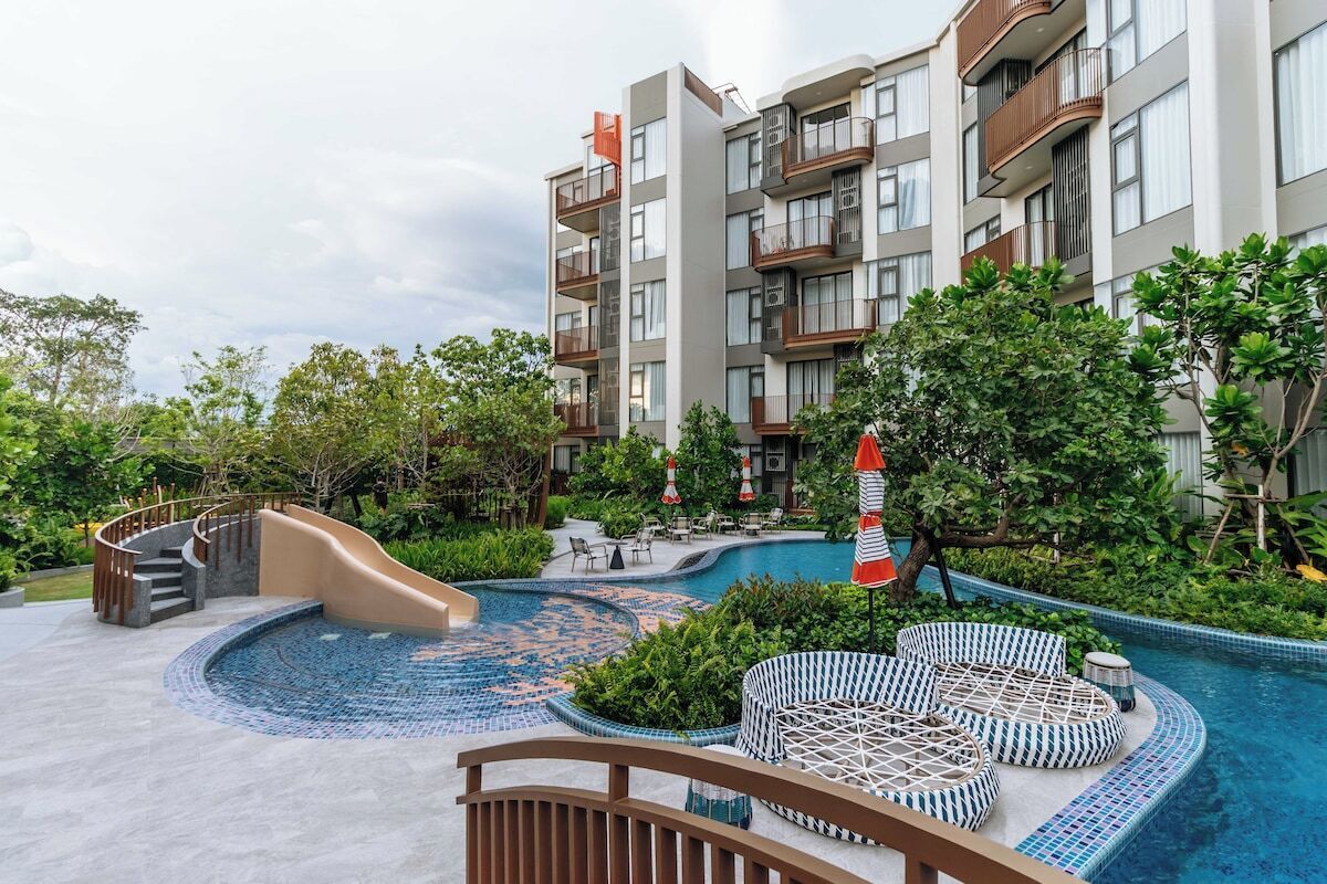 Un hotel con piscina, mobiliario exterior y una escalera que lleva al edificio.