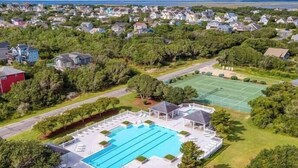 Vista aérea de uma área residencial com piscina, quadras de tênis e casas.