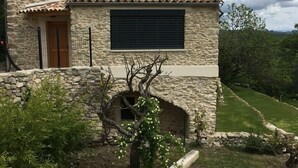 Une maison en pierre avec un toit de tuiles, une fenêtre avec des volets et une petite porte.