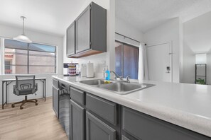 Une cuisine moderne dotée d’un grand îlot central, d’un évier double et d’un coin repas avec une chaise et une table.