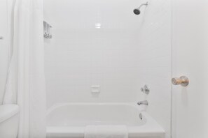 Une salle de bain blanche avec une baignoire, une douche et des toilettes.