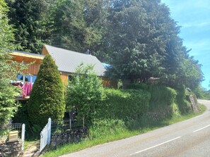 A wooden cabin with a sloped roof, surrounded by dense greenery and a stone wall. - Vrbo Property (Boussenac)