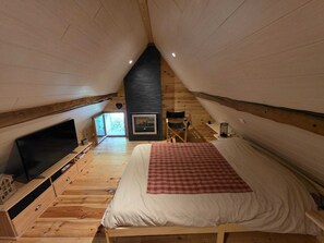Une chambre à coucher avec un lit, une télévision, une cheminée et une fenêtre.