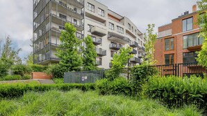 Ein mehrgeschossiges Wohnhaus mit Balkonen, einer Ziegel-Fassade und einer umlaufenden Grünanlage.
