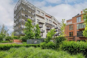Ein mehrgeschossiges Wohnhaus mit Balkonen, einer Ziegel-Fassade und einer umlaufenden Grünanlage.