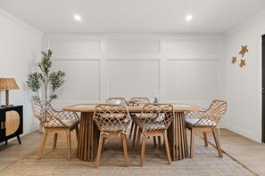 A dining area with a round table, six wicker chairs, a black cabinet, and a plant. - Steps to Beach Access | Gated Holiday Isle Townhome (Destin)