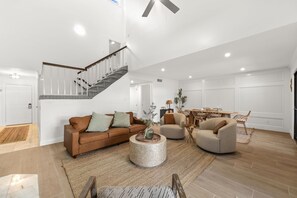 Un salon spacieux avec un escalier, un coin repas et une grande fenêtre.