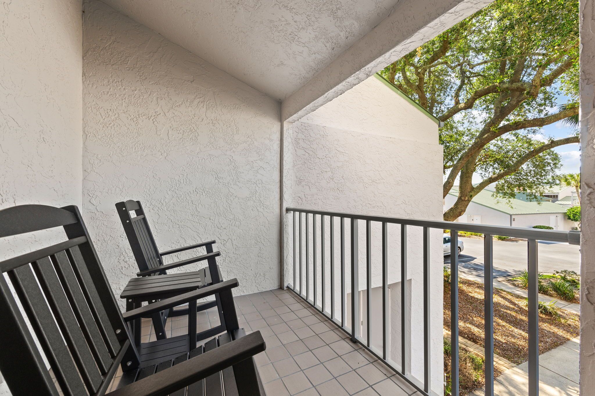 Un balcon donnant sur un arbre et une rue.