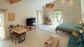 A spacious living area with a dining table, sofa, and a stone accent wall. - ⭐​ The Colibris Loft ⭐​ (Mirabel-et-Blacons)