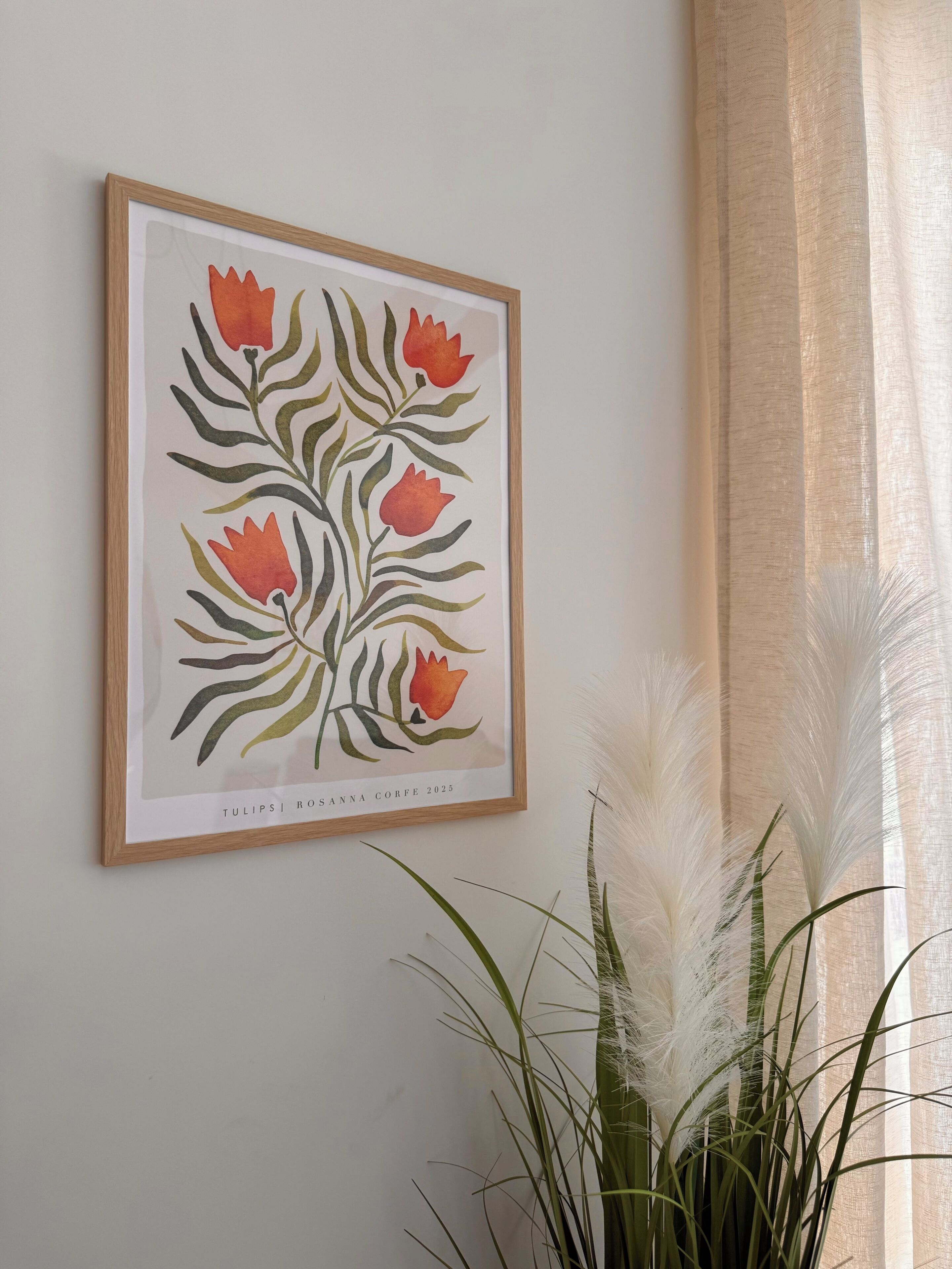 A framed botanical illustration on a wall, with a potted plant in the foreground.