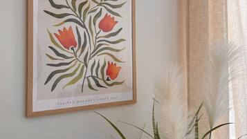 A framed botanical illustration on a wall, with a potted plant in the foreground.