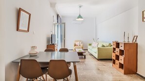 Een moderne woonkamer met een eethoek, een bank, een televisie en een kast.
