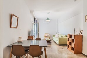 Moderni olohuone, jossa on ruokailutila, sohva, televisio ja kaappi.