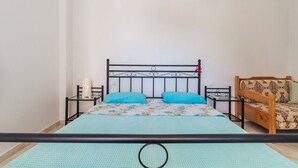 Een kamer met een bed, twee nachtkastjes, een houten bankje en een bed met een decoratief sprei.