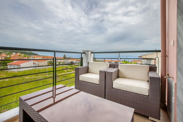 Ein Balkon mit Korbmöbeln und Blick auf Häuser.