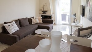 En moderne stue med en hjørnesofa, et rundt sofabord og et spisebord med hvide stole.