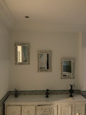Ein Badezimmer mit drei Spiegeln, einem Waschbecken und einem Schrank mit Dekoration.