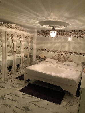 Ein Schlafzimmer mit einem großen Bett, einem Kleiderschrank mit Spiegeln und einer Deckenleuchte.