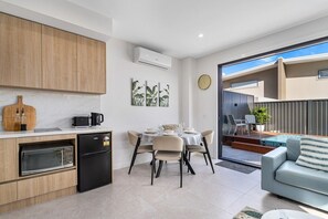 Eine moderne Küche mit Essbereich, einem kleinen Kühlschrank und einer Sitzecke mit Sofa und Tisch.