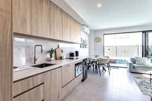 Eine moderne Küche mit Holzschränken, einer eingebauten Spüle und einem Essbereich mit Tisch und Stühlen.