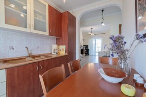 A kitchen with wooden cabinets, a dining table, chairs, and a vase with flowers. - Nerea Beach House by Rentals Pro - Mouries Halkidiki (Mouries)