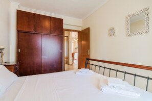A hotel room with a large bed, wooden wardrobe, and a mirror on the wall. - Nerea Beach House by Rentals Pro - Mouries Halkidiki (Mouries)