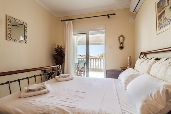 A hotel room with a bed, a window, a balcony, and a door. - Nerea Beach House by Rentals Pro - Mouries Halkidiki (Mouries)