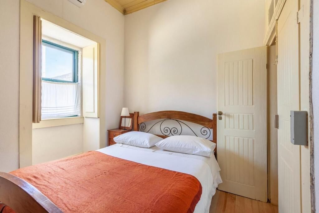 A bedroom with a bed, a nightstand, a window, and a door.