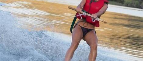 A person water skiing on a calm body of water with a hilly landscape in the background.