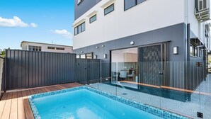 Un edifici modern amb una piscina, un porxo cobert i una entrada tancada amb vidre.