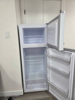 Un refrigerador abierto con varios estantes y un compartimento congelador.