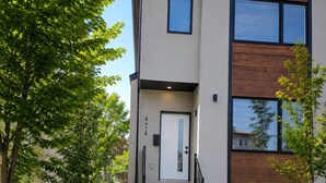 A modern two-story building with a concrete staircase leading to a white door marked with the number 474. - The Cozy Corner Home (Winnipeg)